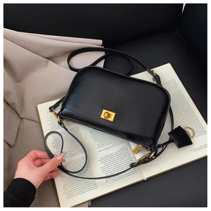 Close-up of a black crossbody bag featuring a classic golden metal twist-lock and matte finish