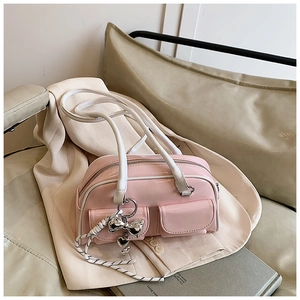 Detalle de bolso en charol rosa con bolsillos y dijes de corazón sobre una chaqueta