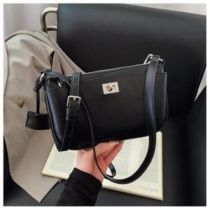 Detail of a black PU leather crossbody bag with silver twist lock and adjustable strap