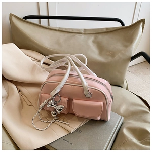 Detalle de bolso en charol rosa con bolsillos dobles frontales y colgante de lazo plata