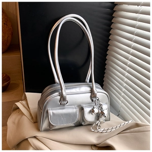 Detalle del bolso Boston plateado con dos bolsillos delanteros y un colgante de lazo plateado