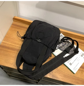 Detail of black tactical nylon chest bag with drawstring design on wooden background
