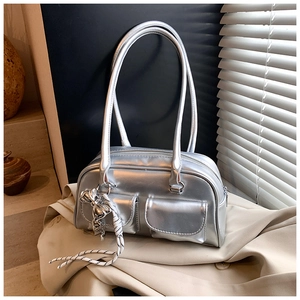 Detalle de bolso Boston plateado con bolsillos dobles y colgante de lazo Y2K