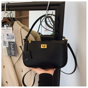 Detail of a chic black leather crossbody bag featuring a classic gold metal twist lock
