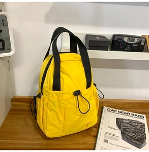 Close-up of lightweight yellow nylon bag with drawstring pocket and sturdy black handles
