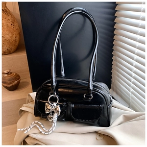 Detalle del bolso Boston negro brillante con bolsillos delanteros y colgante de mariposa