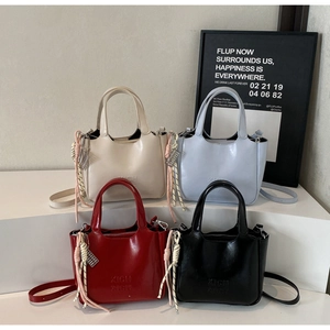 Dettaglio di piccole borse tote in quattro colori con logo XICH XICH inciso sul davanti
