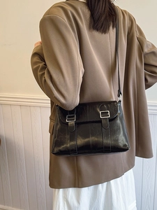 Petit sac à bandoulière noir minimaliste avec boucles porté avec un blazer marron chic