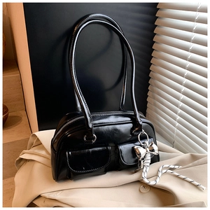 Detalle del bolso de charol negro con dos bolsillos delanteros y colgante mariposa