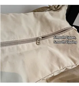Close-up of smooth metal zipper and textured canvas fabric on the beige tote bag
