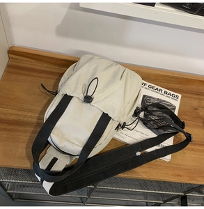 Close-up of beige nylon crossbody bag with drawstring closure on a wooden surface