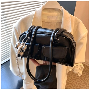 Detalle de bolso de hombro negro brillante con dos bolsillos frontales y colgante Y2K
