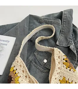 Detail of handmade crochet shoulder bag featuring sunflower patterns and woven strap