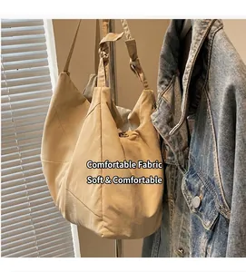 Detail of a beige canvas tote bag with unique knotted handle hanging on a hanger