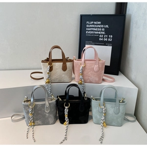 Detailed close-up of textured leather bucket bags in five colors with charm accessories