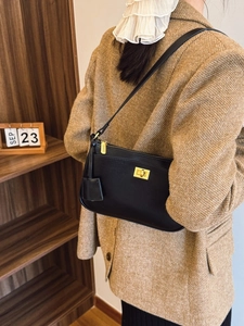 Classic black leather crossbody bag with gold hardware worn with a tweed blazer