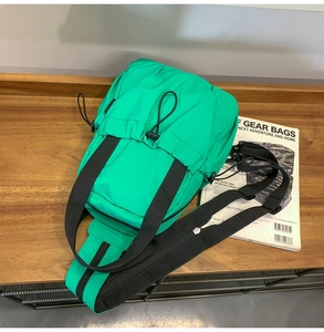 Macro view of bright green functional nylon shoulder bag with drawstring closure on wood