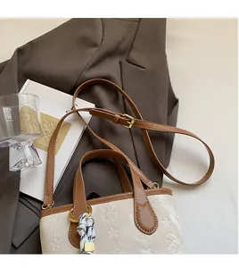 Detail of adjustable leather strap and textured bucket bag with metallic ring hardware