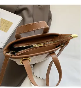 Close-up of smooth gold-tone zipper and textured beige fabric on the bucket bag