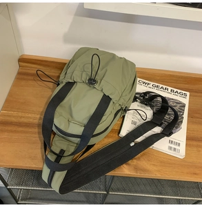 Olive green utility crossbody bag with drawstring pocket and black adjustable strap