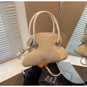 Detail of a chic cream shell bag with dual handles and adjustable shoulder strap