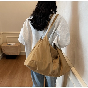 Oversized khaki canvas tote bag shown on shoulder in a minimalist indoor setting