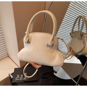Macro detail of glossy cream shell bag with silver bead hardware and polished finish