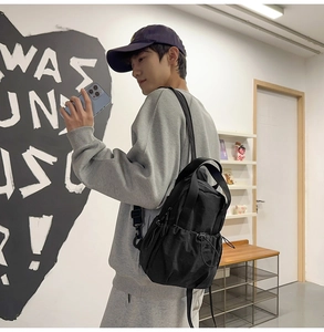 Rear view of a model wearing the black nylon multi-functional backpack in a lifestyle setting