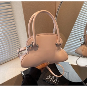 Close-up of pink shell-shaped handbag with polished silver hardware and slim shoulder strap