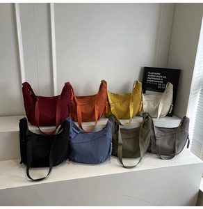 Detailed display of nylon crescent bags in eight solid colors with wide adjustable straps