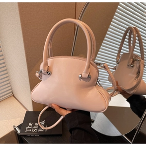 Mirror reflection showing both sides of a pink shell shaped handbag with silver hardware