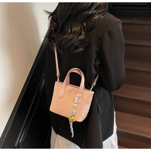 Pink bucket bag with star patterns and silk scarf shown on a shoulder in a lifestyle setting