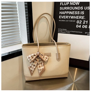 Detail of beige woven tote bag with houndstooth silk scarf under natural window light
