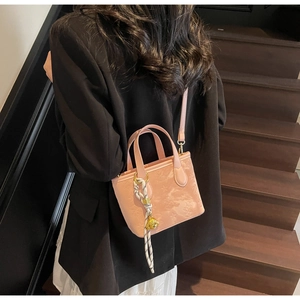Pink bucket bag with star patterns and a gold lion pendant shown on a model