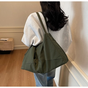 Detail view of olive green quilted puffer tote bag on shoulder for daily commute