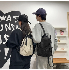 Rear view of couple wearing minimalist nylon outdoor backpacks in black and beige