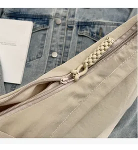 Close-up of smooth metal zipper and decorative woven rope puller on khaki crescent bag