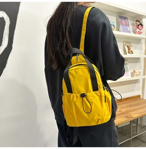Detailed view of yellow mini nylon backpack with adjustable drawstring pocket and side straps