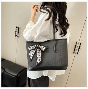 Detail of woven texture tote bag with houndstooth bow accessory on leather strap