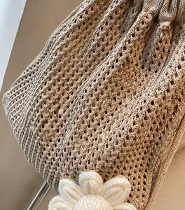 Detalle del bolso de playa de ganchillo beige calado con flor de punto decorativa
