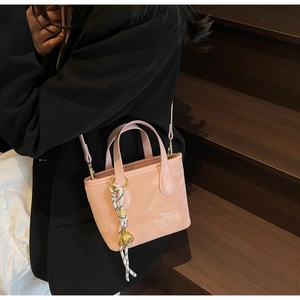 Detail of pink mini tote bag with polka dot scarf and golden puppy charm on model