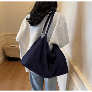 Detailed back view of a large navy blue commuter tote bag shown on a model in a minimalist room