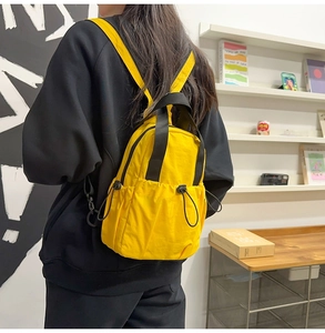 Detail of a bright yellow nylon backpack with side bungee cord pocket and black straps