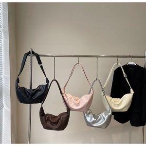 Five assorted colors of large capacity faux leather crescent shoulder bags on a rack