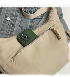 Detail of beige nylon crescent bag featuring front zipper pocket and ample storage space