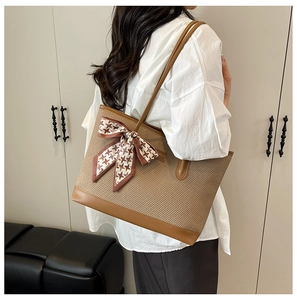 Detailed shot of large woven tote bag with brown faux leather trim and silk scarf accent