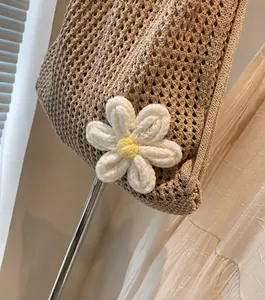 Detalle de bolso de paja trenzada con un adorno de flor blanca tejida a ganchillo