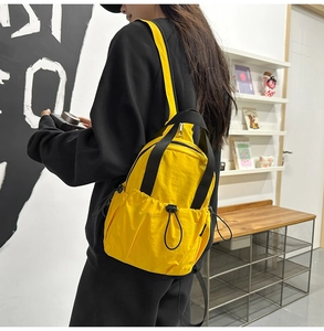 Detail view of bright yellow nylon backpack featuring drawstring pockets and black straps