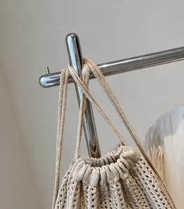 Primer plano de las correas de punto y el cordón ajustable del bolso de playa beige tejido
