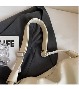Detail of adjustable faux leather shoulder strap with metallic buckle on a beige tote bag